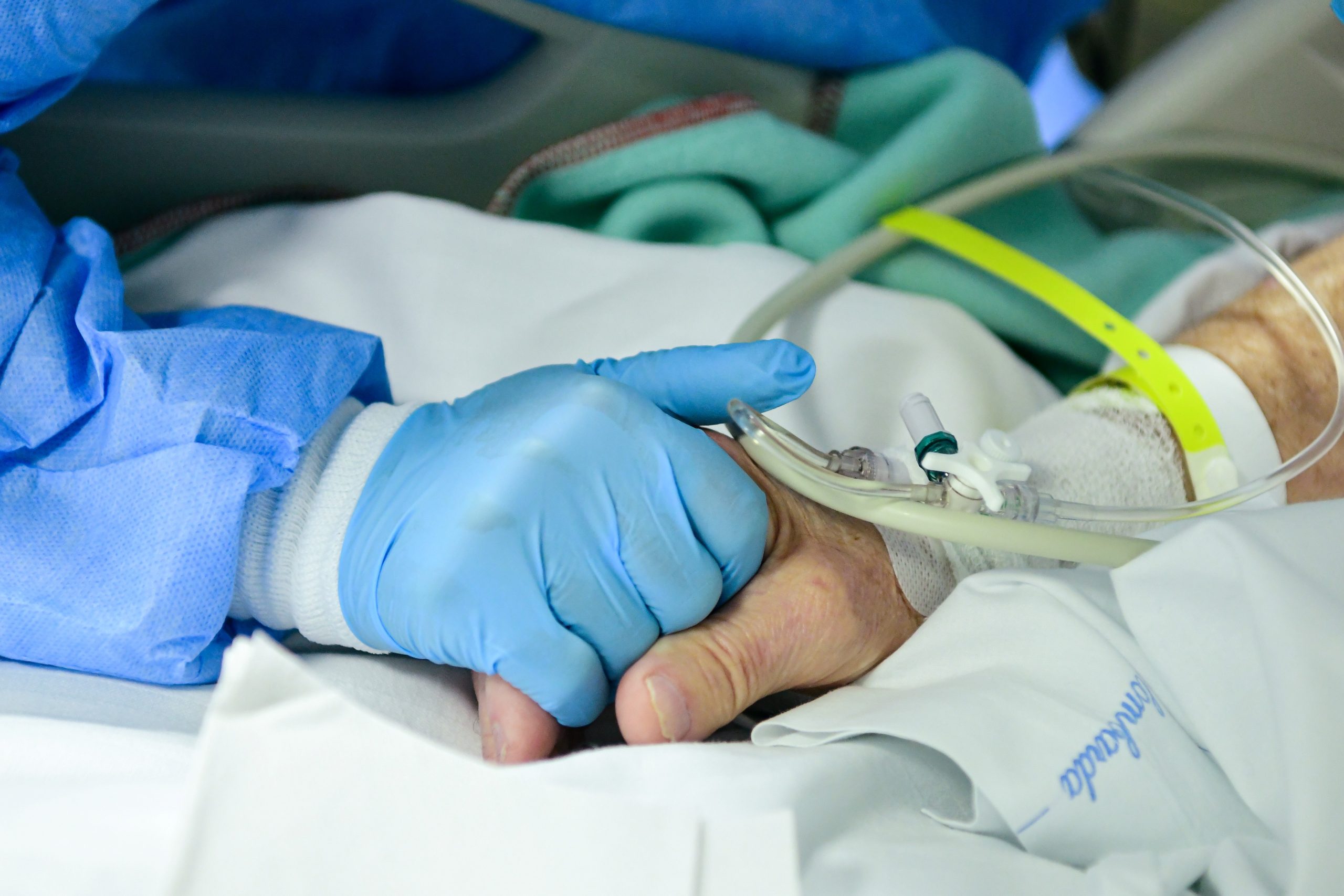 A member of the medical staff comforts and holds the hand of a patient infected by the novel coronavirus at the COVID-19 division at the ASST Papa Giovanni XXIII hospital in Bergamo, on April 3, 2020. - Italy's three-week lockdown to stop the spread of COVID-19 has been extended through at least mid-April and its economy is expected to suffer its biggest peacetime shock since World War II. (Photo by Piero CRUCIATTI / AFP)